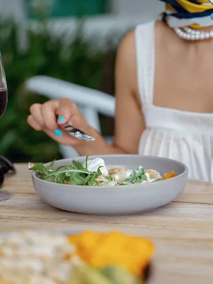 A close-up shot of a fresh salad at Olive Bistro. The focus is on the food, with the model blurred in the background, highlighting the culinary experience.