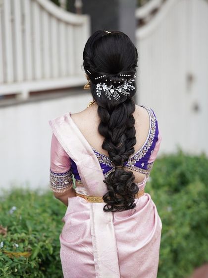 A modern take on a traditional braid. This hairstyle features a voluminous braid with loose, curled ends and is decorated with delicate, sparkling hairpins.