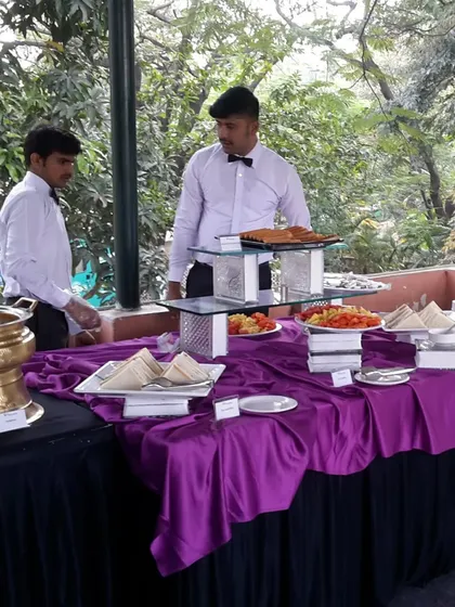 Our staff attending to the buffet at an outdoor party. They ensure the food is always well-stocked and the serving area remains clean and presentable.