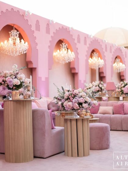 A lounge area at the 'Echoes of Pink' wedding, featuring modern furniture, crystal chandeliers, and custom-built arched backdrops inspired by Qatari architecture.
