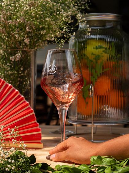 A guest enjoying a glass of wine at our picnic, with a vibrant red fan adding to the festive atmosphere.