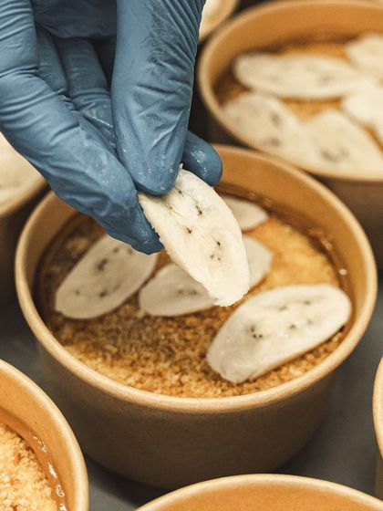 Carefully placing sliced bananas onto the Banoffee Pie base.