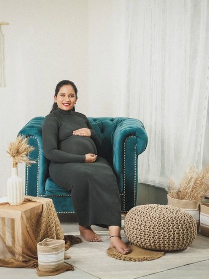 "Nine months preparing to fall in love for a lifetime." A calm and happy portrait of a mom-to-be in a simple grey dress, seated comfortably in my cozy studio corner.
