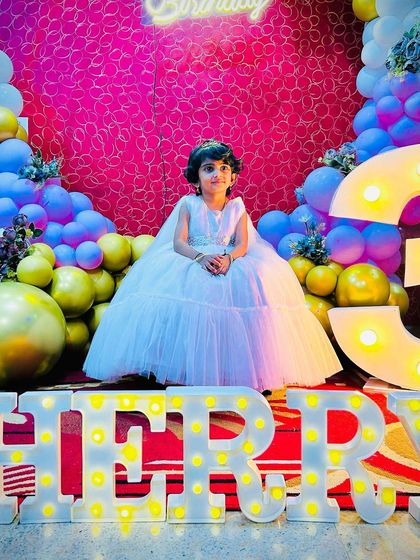 The birthday girl, Cherry, sitting like a princess in front of her name in marquee letters. The vibrant balloons and glowing number '3' make for a picture-perfect birthday scene.