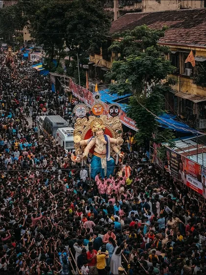 An aerial drone shot showing the massive crowd accompanying the idol through the streets of Chinchpokli. This perspective highlights the sheer scale of the festival.