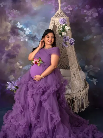 A portrait of a queen on her throne. The macrame swing, adorned with purple flowers, perfectly frames this mama-to-be, making her look absolutely regal.
