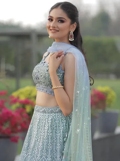 A side profile in the ice blue lehenga, highlighting the delicate embroidery and the beautiful ombre effect of the dupatta.