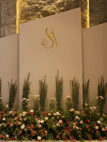 Modern elegance is one of our signatures. This chic Roka ceremony backdrop features a clean, multi-panel design with a custom gold monogram and a wildflower-inspired floral base, perfect for a sophisticated celebration.
