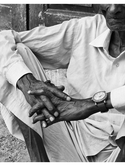 A close-up on the man's hands, weathered and expressive, resting one over the other. A story in every line.