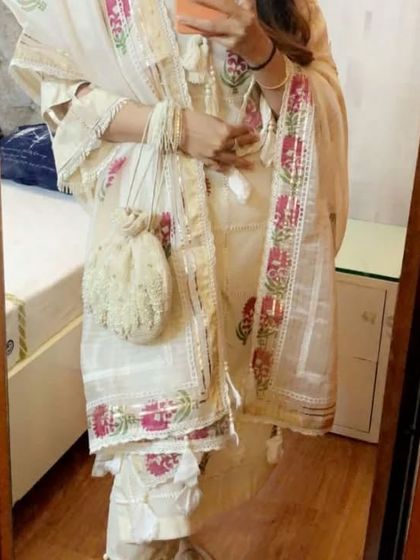 A client looking lovely in a custom off-white suit with pink floral block prints. The look is completed with a matching embroidered potli bag, showcasing how we can create coordinated accessories.