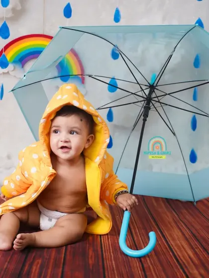 This baby is all set for a rainy day with his yellow raincoat and blue umbrella. A perfect setup for a playful monsoon shoot.
