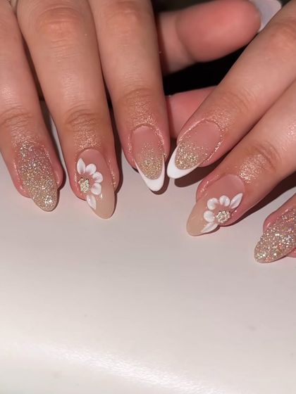 A perfect design for a wedding or special occasion. These almond nails feature a glittery French tip with 3D white flowers and rhinestone centers.