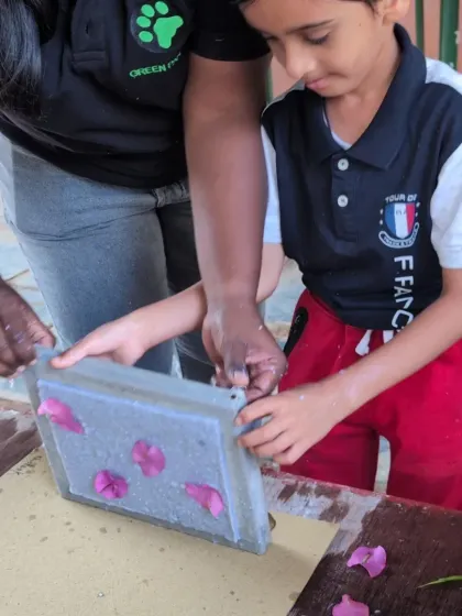 A young boy adds flower petals to his handmade paper, a beautiful way to personalize his creation and connect with nature.