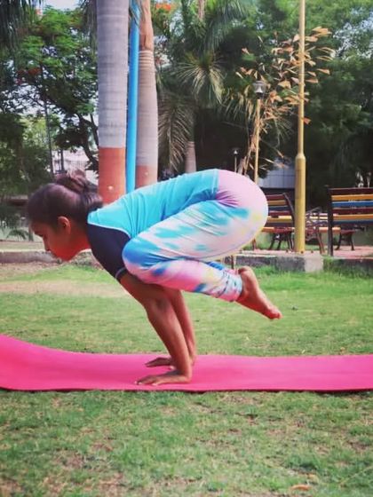 Finding stability in Bakasana (Crow Pose) in a park. This arm balance is a great confidence builder and strengthens the entire upper body.