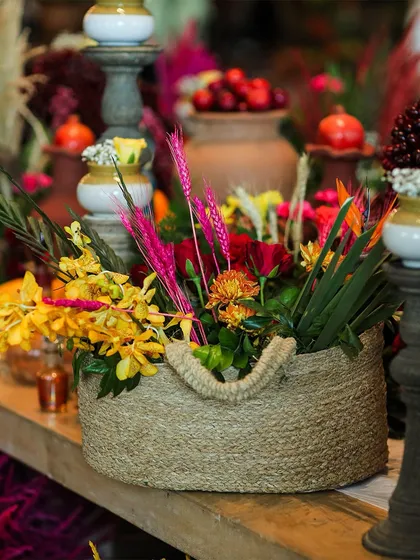 A close-up of a rustic jute basket filled with a vibrant mix of flowers. It's these small, thoughtful details that bring a decor theme to life.
