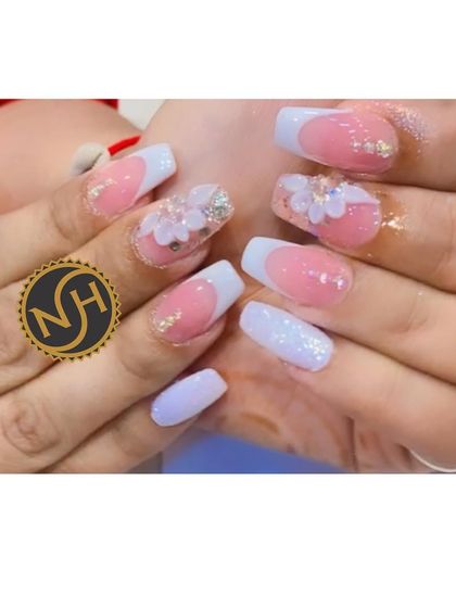 A beautiful example of a French manicure with 3D floral accents. The soft white tips and pink base are the perfect canvas for these delicate, handcrafted flowers.