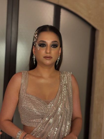 The client looks stunning in her sequined saree. The sleek, straight hair with the side accessory is a modern take on event hair, perfect for a high-fashion look.