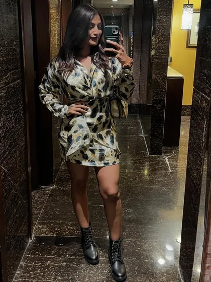 A mirror selfie showing off this fun animal print wrap dress. Paired with black combat boots, it creates a look that's both trendy and edgy.