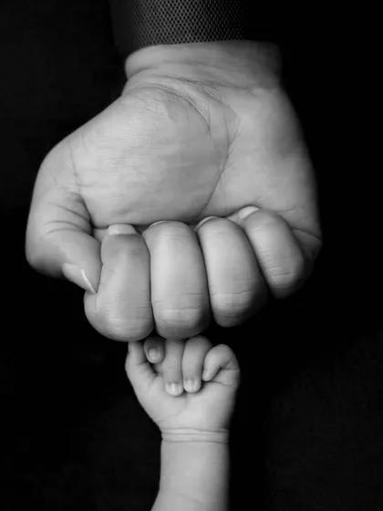 A powerful black and white image of a baby's tiny fist against their parent's. The contrast in size is a poignant reminder of how quickly they grow.