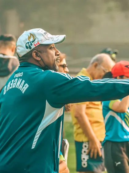 A senior coach directs his players from the sideline, his experience guiding the team's performance.
