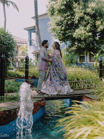 A romantic portrait on a small bridge over a stream, set in a lush garden. The setting adds a touch of fairytale charm.