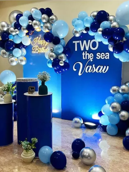 We love getting creative with unique themes like this 'Two the Sea' concept for a second birthday. This setup features a striking color palette of deep and light blues with silver chrome balloons, custom backdrops, and matching pedestals for a modern and stylish party.