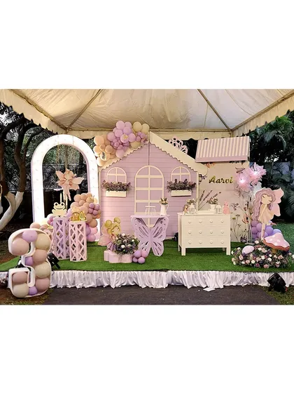 Welcome to a fairy's dream home. This enchanting setup for a third birthday features a life-sized pastel purple playhouse, a custom butterfly-shaped table, and a glowing number '3' filled with balloons, creating a magical atmosphere for the little ones.
