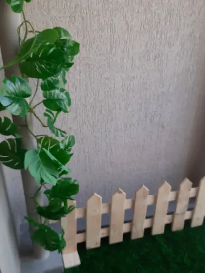 A small pinewood picket fence used as a border for an artificial grass patch in a balcony. It's a simple touch that helps define the space and adds a classic garden feel.