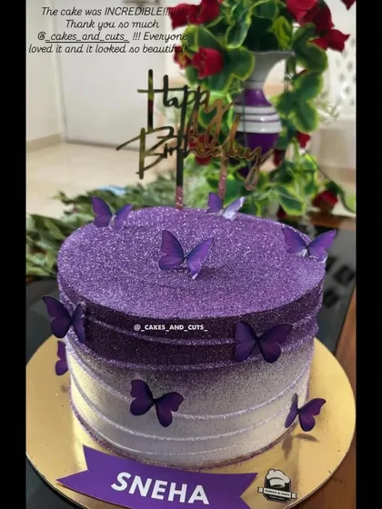 A sparkling purple ombre cake covered in edible glitter and decorated with butterflies, personalized for Sneha.