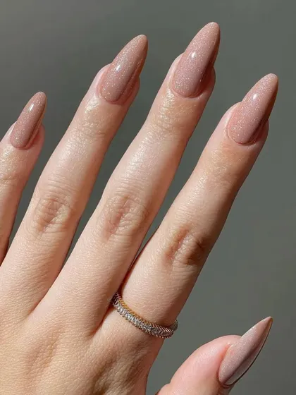A full view of this stunning nude glitter manicure. The long, elegant shape of the nails combined with the sophisticated sparkle makes this a perfect choice for a bride who wants a glamorous yet understated look.