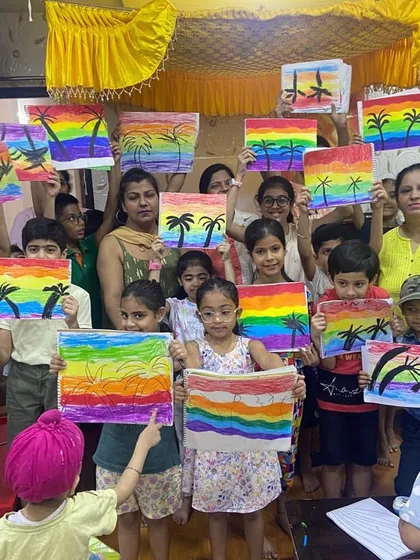 Look at those proud smiles. This is the result of a fun group session on landscape painting, where students learned about color blending to create these vibrant rainbow scenes.