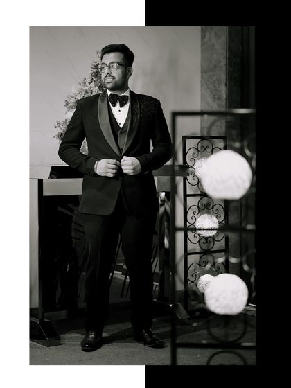 A timeless black and white portrait of the groom, capturing a moment of quiet confidence.