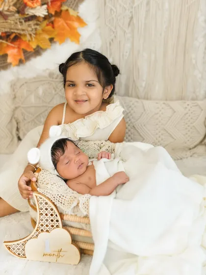 One month old and already so loved. Including older siblings in newborn milestone shoots creates such precious memories, like this sweet moment with big sister smiling for the camera.