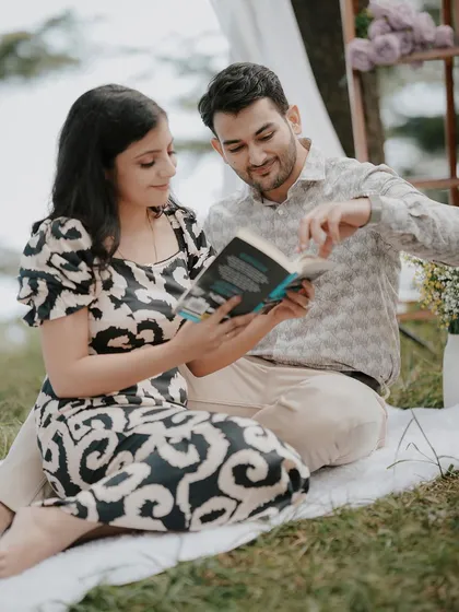 A candid moment of the couple sharing a book during their picnic-themed shoot. It's these small, personal details that make a pre-wedding session unique and story-driven.