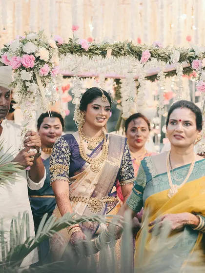 The bride's grand entrance, surrounded by family. Her glowing makeup and traditional attire make her the center of attention.