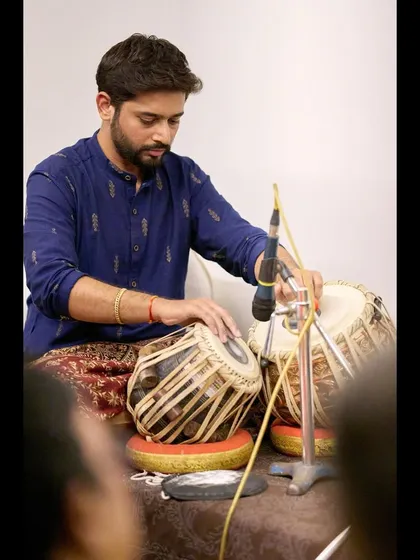 A focused moment during the sitar recital, ensuring my rhythm perfectly complements the melody.