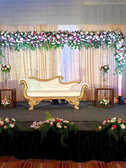 Here is another look at a popular floral arch stage design. The combination of a full floral arch, soft curtaining, and coordinated floor arrangements creates a complete and polished look for any wedding event.