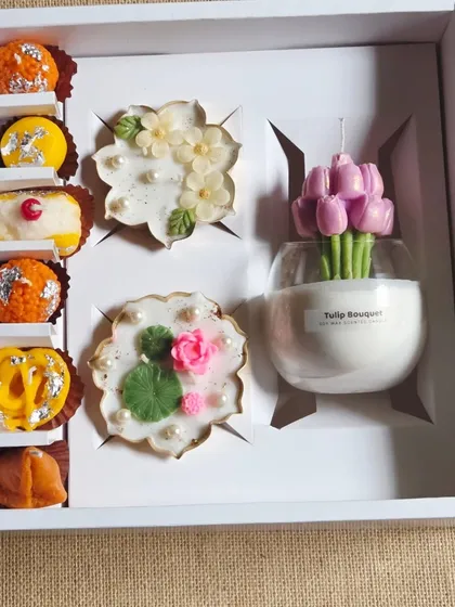 A premium Diwali gift box featuring a mix of my creations. It includes a tulip bouquet candle, two floral urli candles, and a set of six food-inspired candles.
