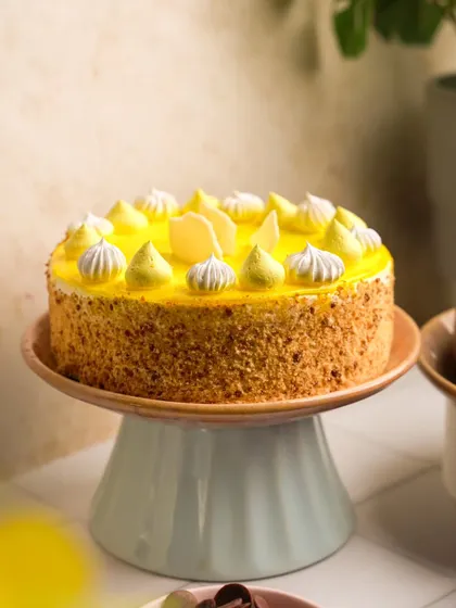 A bright and cheerful shot of a mango cake on a pastel cake stand. This image was part of a larger campaign for a dessert brand, designed to feel fresh and summery.