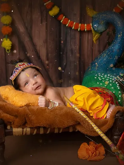 A wide-eyed baby Krishna. This little one was curious about the whole setup, including the beautiful peacock prop.