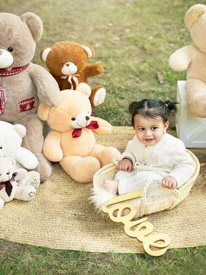 Surrounded by her favorite teddy bears, this little one is enjoying her outdoor party. The "love" sign adds a sweet touch to the scene.