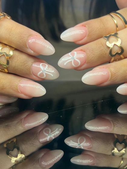 A lovely French ombre set with delicate white bows painted on accent nails, creating a soft and feminine design.