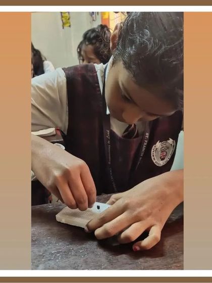 A student carefully works on assembling a small part of her project. This close-up shot emphasizes the fine motor skills and attention to detail that students develop in our classes.