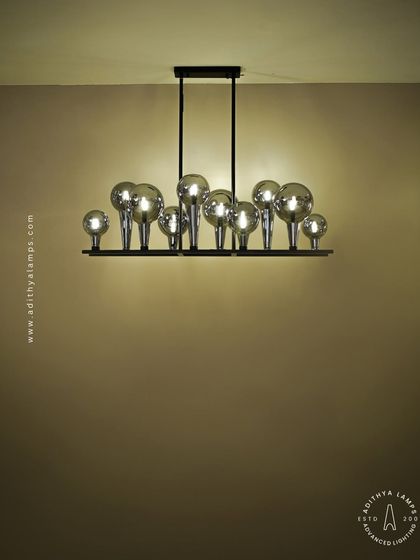 A playful yet chic linear chandelier featuring a series of chrome-finished glass bubbles. The highly reflective surface and modern design make it a striking addition to a kitchen island or a contemporary dining space.