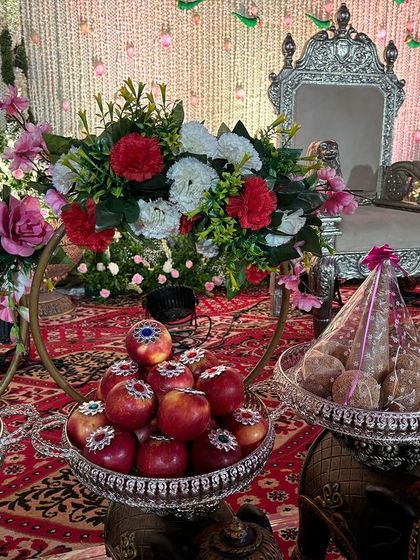 A close-up of the offering bowls filled with apples and traditional sweets.