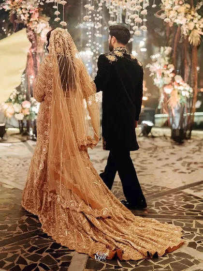 The couple walking away, showing the stunning back of the groom's sherwani and the bride's flowing train. A perfect exit.