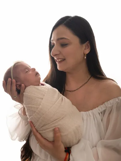 A mother holds her tiny newborn in her hands, a beautiful pose that shows just how small and precious they are.