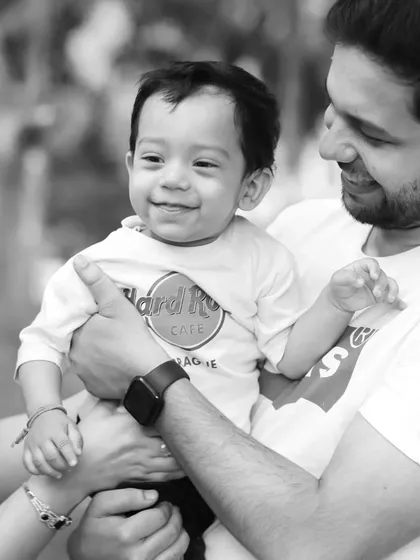 A tender black and white photo of a father holding his smiling son. This style adds a timeless and emotional quality to the portrait.