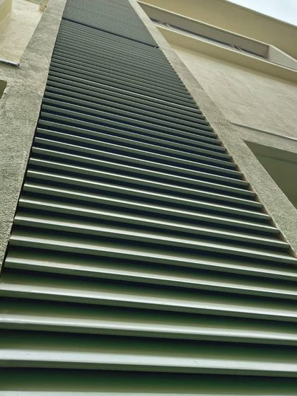 A close-up view of our sleek metal louvers installed on a residential building. This low-angle shot highlights the clean lines and precision of the installation, which provide both privacy and architectural style.