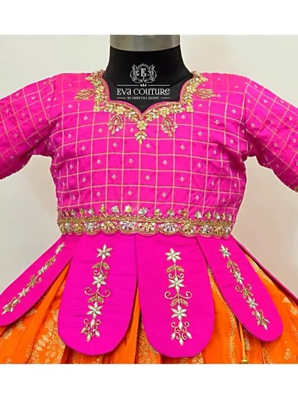 This close-up shows the unique details of a pink blouse, including a grid pattern, mirror work, and an embroidered petal-style peplum.